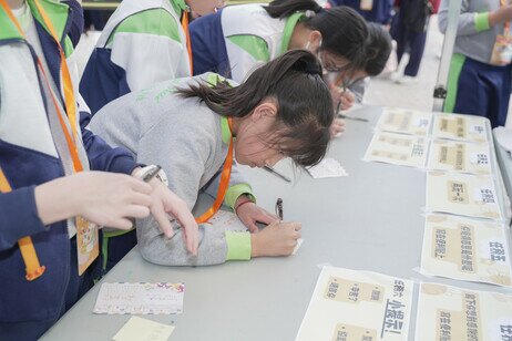 In front of the booth games, the primary school students write down the people and things for which they wish to express gratitude