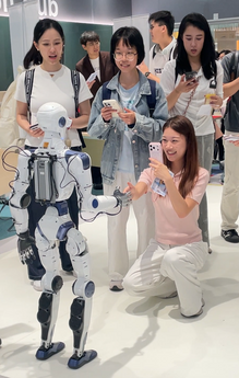 A participant interacts with the humanoid robot by shaking hands at the roadshow